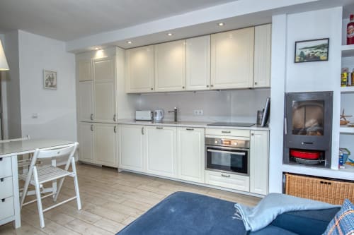 Cuina moderna i sala d'estar en casa rural de Palafrugell amb mobiliari blanc, electrodomèstics encastats i mobles confortables