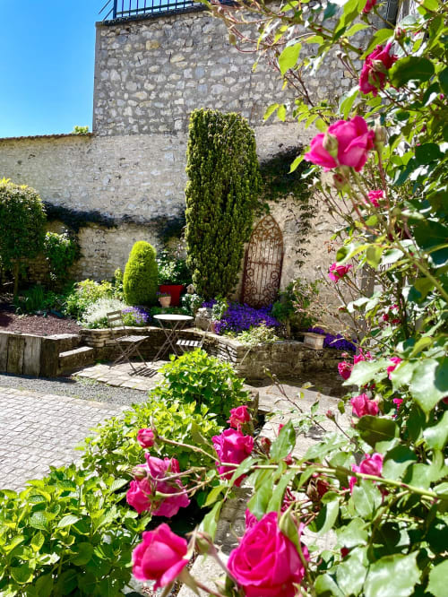 Charming garden courtyard at Maunoury Citybreak hotel in Chartres with blooming magenta roses, stone walls, and seating area