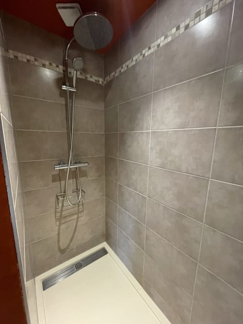 Modern shower enclosure with gray tiled walls and rainfall showerhead at Maunoury Citybreak in Chartres