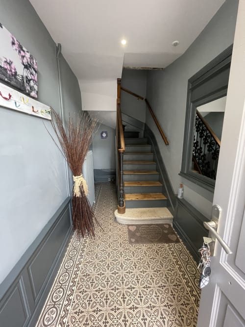 Hallway with patterned tile floor and wooden stairs at Maunoury Citybreak apartment in Chartres
