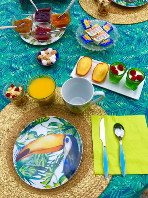 Tropical breakfast setup at Maunoury Citybreak with toucan-patterned plate, pastries, juice, and green napkins