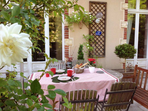 Charming garden dining setup at Maunoury Citybreak in Chartres with pink-striped tablecloth, place settings, fresh flowers,