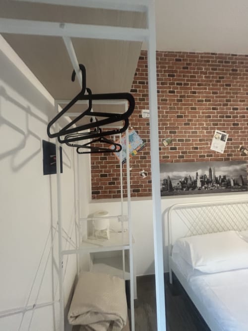 Camera da letto al B&B GATE 10 Fiera Bologna con muro in mattoni, struttura letto in metallo e stendino con grucce