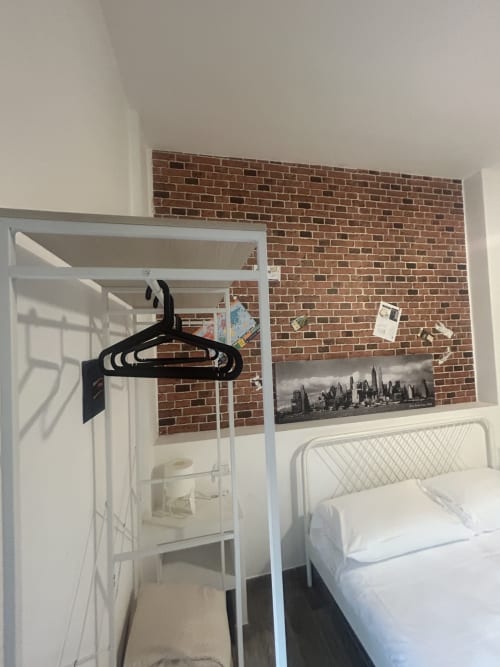 Camera moderna a B&B Gate 10 Bologna con letto a castello in metallo bianco, muro in laterizio a vista e poster dello skyline cittadino