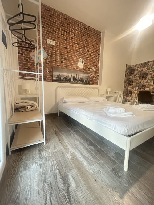 Camera JET del B&B GATE 10 Fiera Bologna: letto matrimoniale bianco con biancheria bianca, parete in mattoni a vista, mensole sospese, legno scuro