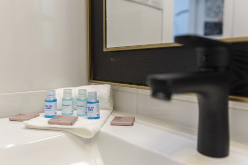 Bathroom sink counter at G&H Apartments in Jerez with toiletries, hand soap, and black faucet