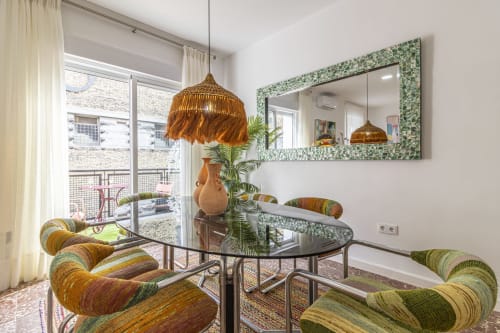 Modern apartment lounge at G&H Apartments Jerez with striped chairs, glass table, gold pendant lights, and city views