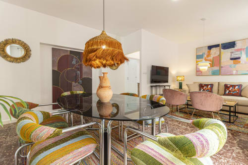 Modern apartment living room at G&H Apartments, Jerez de la Frontera, with round glass table, colorful chairs, and city views