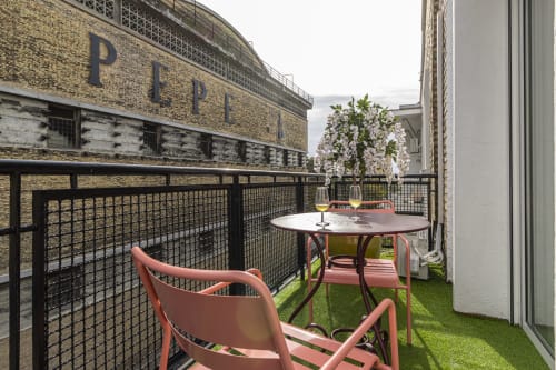 Rooftop terrace at G&H Apartments with pink chairs, round table, flowering vines, and city views in Jerez de la Frontera