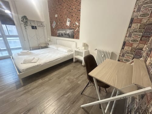 Camera moderna di B&B Gate 10 Bologna con letto bianco, scrivania, parete in mattoni e pavimento in parquet