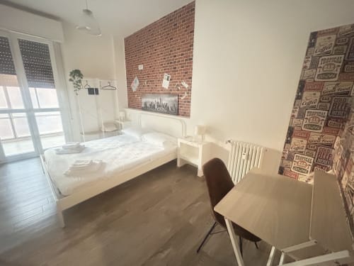 Camera moderna di B&B GATE 10 a Bologna con letto bianco, muro in mattoni, scrivania e accesso alla terrazza