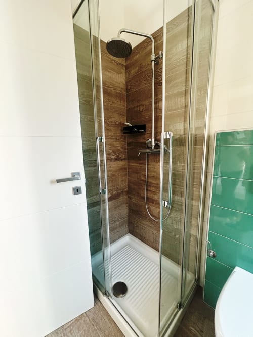 Bagno moderno con cabina doccia in finto legno, soffione pioggia e pareti bianche presso B&B GATE 10 FIERA Bologna