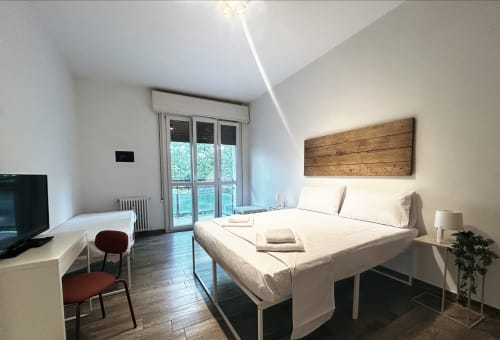 Camera moderna a B&B GATE 10 FIERA BOLOGNA con letto matrimoniale, testiera in legno, accesso alla terrazza e arredamento minimale a Bologna