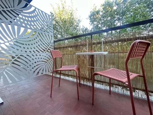 Moderna zona lounge del B&B Gate 10 Fiera Bologna con sedie rosse, tavolo bianco e pannelli metallici decorativi