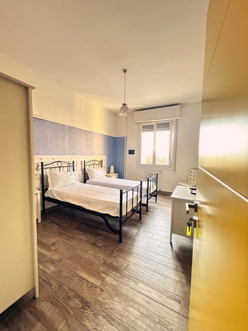 Luminosa camera moderna al B&B Gate 10 Fiera Bologna con letti gemelli, parete blu, pavimenti in legno e luce naturale