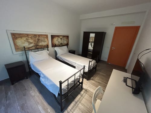 Camera gemelli presso B&B GATE 10 FIERA BOLOGNA a Bologna, con due letti singoli a struttura metallica e testata con opere cartografiche