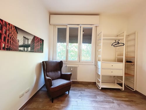 Camera moderna presso B&B GATE 10 FIERA BOLOGNA con poltrona marrone, guardaroba e ampi affacci su Bologna