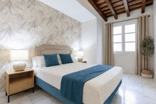 Bright bedroom at G&H Apartments in Jerez with blue accents, wooden beams, and garden views