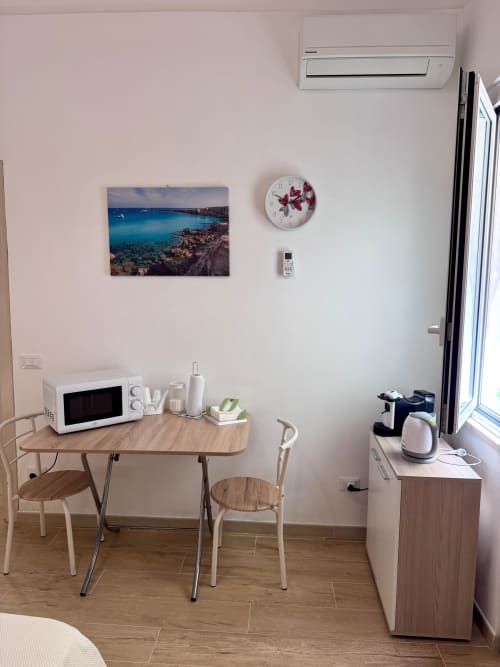 Modern kitchenette in Casa Vacanze La Coccinella apartment, Trapani with microwave, kettle, dining table and coastal wall art
