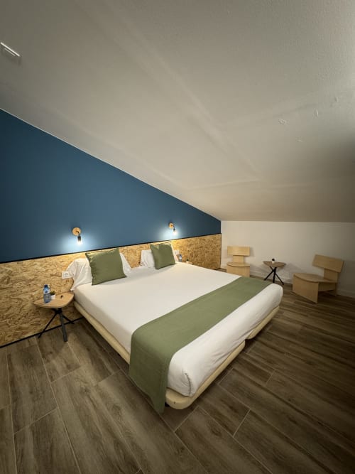 Habitación moderna en Hotel Oreneta en Gironella con cama queen size, pared de acento azul, cabecero de corcho y suelo de madera