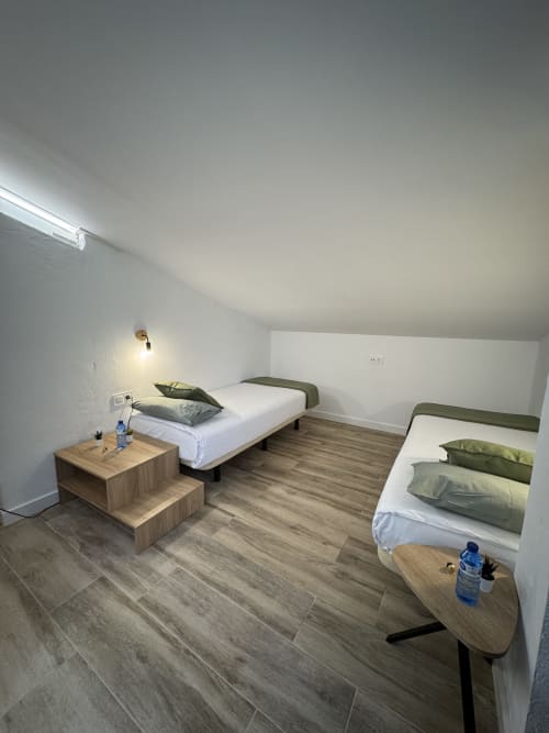 Habitació familiar moderna a l'Hotel Oreneta a Gironella amb dos llits, mobles de fusta i decoració minimalista