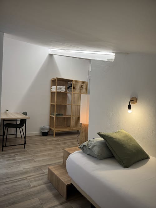 Habitació familiar moderna a l'Hotel Oreneta a Gironella amb llit, emmagatzematge de fusta, escriptori i claraboia en disseny minimalista