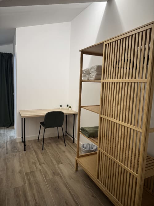 Habitació d'hotel modern a l'Hotel Oreneta amb estanteries de fusta, escriptori, cadira negra i sostre inclinat
