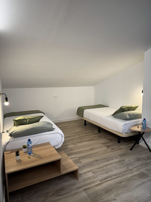 Habitació familiar moderna a l'Hotel Oreneta de Gironella amb dos llits, mobles de fusta i parets blanc brillant