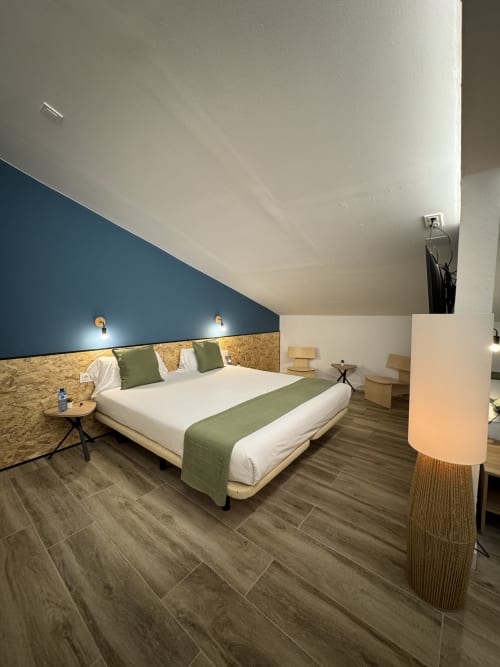 Habitació familiar moderna a l'Hotel Oreneta de Gironella amb paret blava destacada, capçal de fusta i detalls verds
