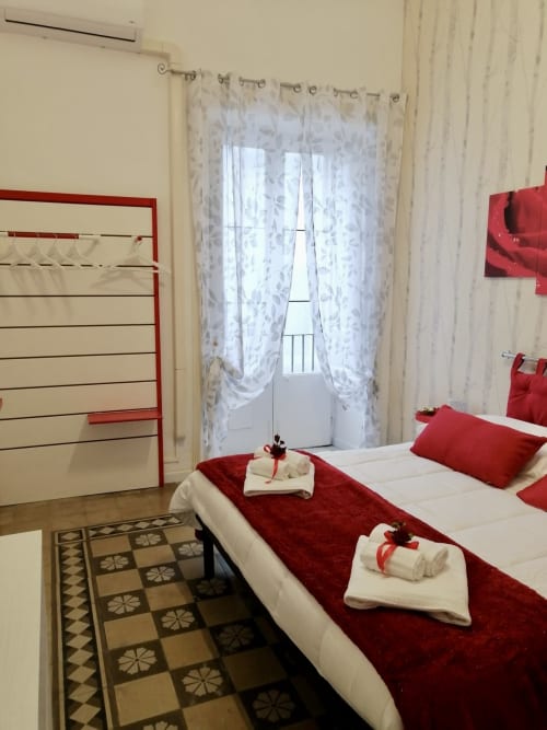 Rosa room at I colori della Sicilia BnB in Caltagirone with red and white decor, balcony view