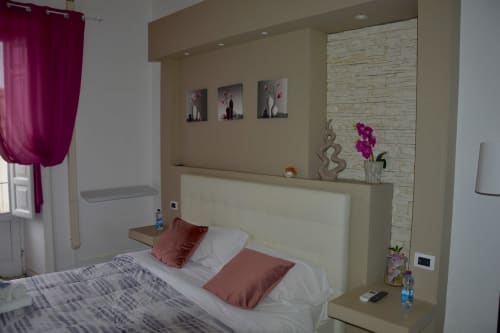 Modern bedroom at I colori della Sicilia in Caltagirone with cream headboard, burgundy pillows, and pink curtains