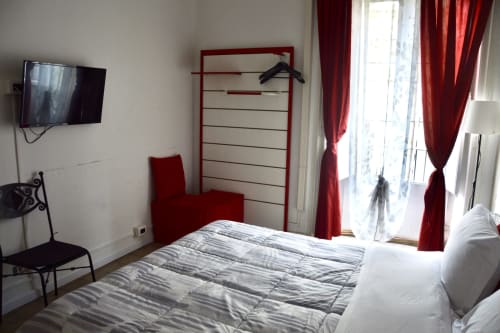 Modern bedroom in Rosa room at I colori della Sicilia B&B, Caltagirone, with striped bedding, red accents, TV, and landmark