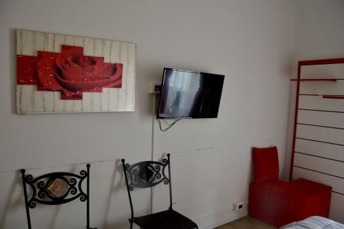 Sicilian-themed room with red rose artwork, flat-screen TV, ornate black chairs, and red accent furniture at I colori della