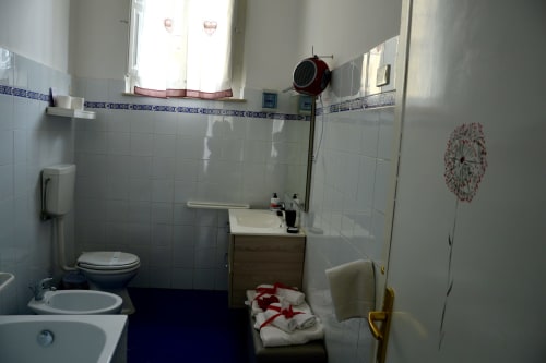 Bright bathroom in Rosa room at I colori della Sicilia B&B in Caltagirone, Sicily with white tiles and decorative red accents
