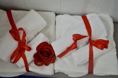 White rolled towels with red ribbons and rose at I colori della Sicilia B&B in Caltagirone