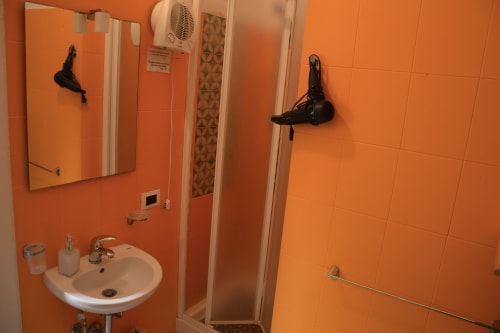 Bright orange bathroom in Wood room at I colori della Sicilia B&B, Caltagirone, with sink, mirror, shower, and wall-mounted