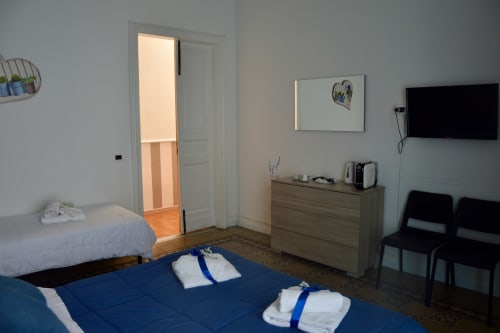 Spacious room at Lavanda B&B in Caltagirone with two beds, dresser, TV, and landmark views, Sicily
