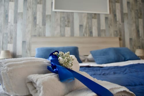 Lavanda room at I colori della Sicilia B&B in Caltagirone with blue ribbon and baby's breath on folded towels, bed with blue