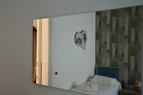 Modern bedroom at I colori della Sicilia in Caltagirone with blue headboard, wood-textured wallpaper, and landmark view
