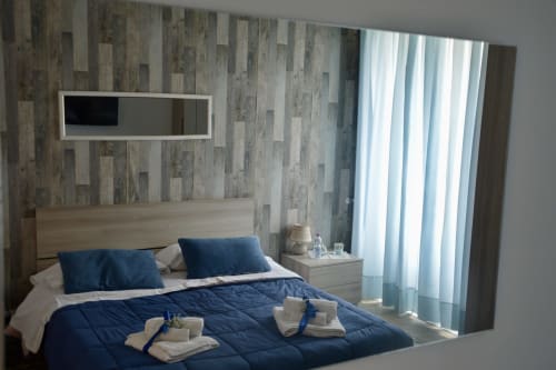 Modern bedroom at I colori della Sicilia with blue bedding, wooden accent wall, and landmark views in Caltagirone