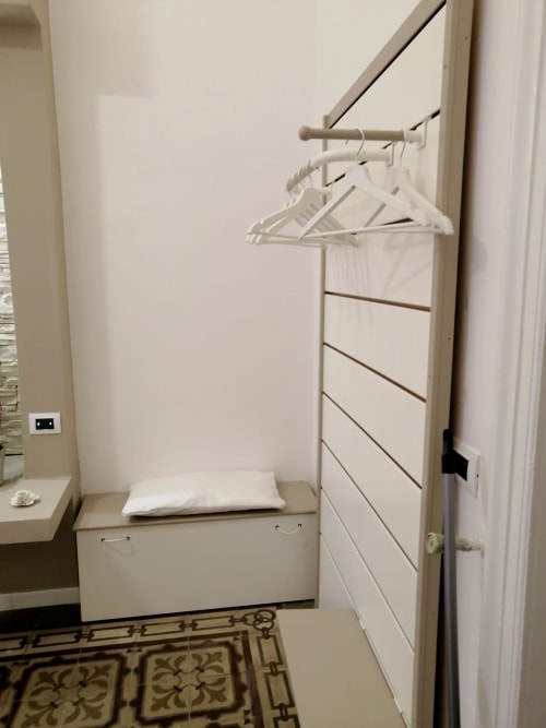Armadio compatto con appendiabiti bianchi e cassetti contenitori nella camera Orchidea presso I colori della Sicilia, Caltagirone