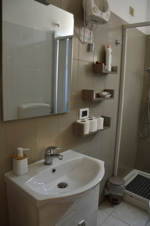 Bagno moderno nella camera Orchidea de I colori della Sicilia B&B, Caltagirone con lavandino bianco, ripiani e zona doccia