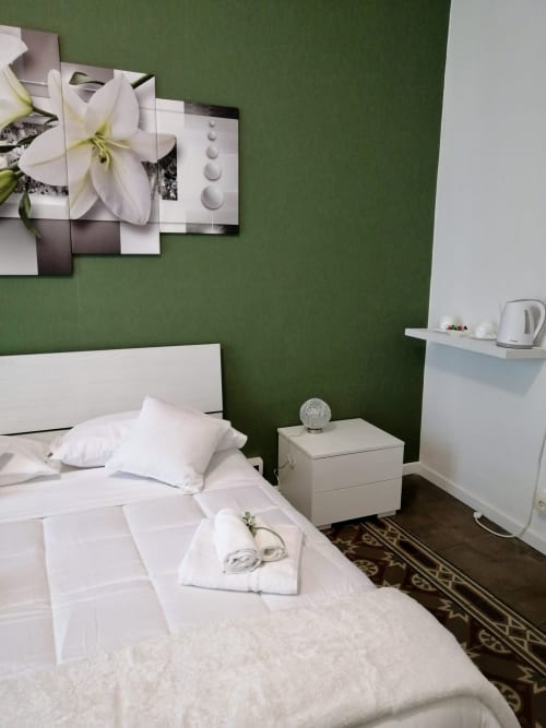 Modern bedroom at I colori della Sicilia in Caltagirone with white bed, green accent wall, and flower artwork