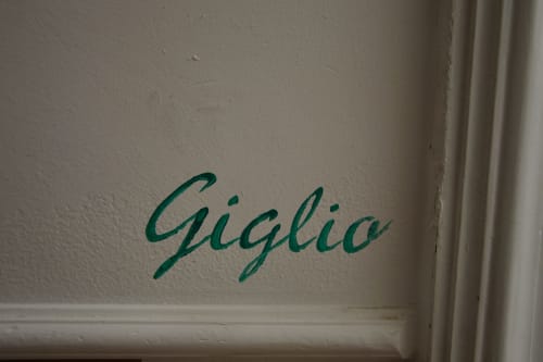 Teal script writing of 'Giglio' on cream wall at I colori della Sicilia bed and breakfast in Caltagirone, Sicily