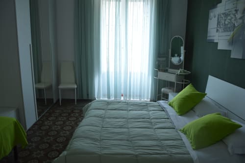 Modern bedroom at I colori della Sicilia in Caltagirone with green accents, white bedding, vanity mirror, and landmark view