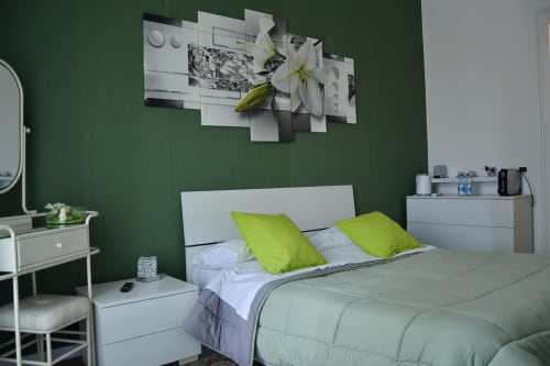 Giglio room at I colori della Sicilia with green walls, white bed, lime pillows, and floral artwork