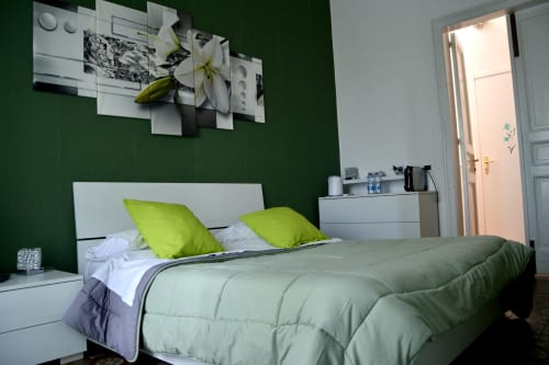 Modern bedroom at I colori della Sicilia with green accent wall, lime pillows, and white furnishings in Caltagirone