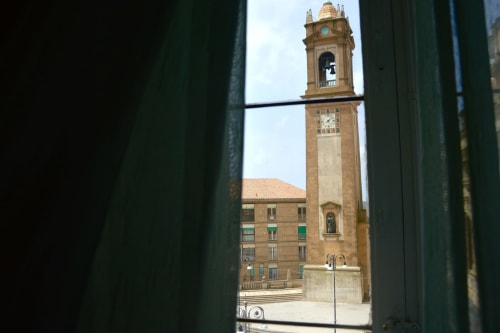 View of Caltagirone's iconic clock tower landmark framed through a window at I colori della Sicilia B&B