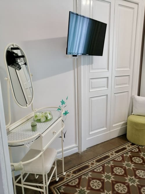 Modern bedroom in I colori della Sicilia B&B with wall-mounted TV, white vanity desk with mirror, and decorative plants in