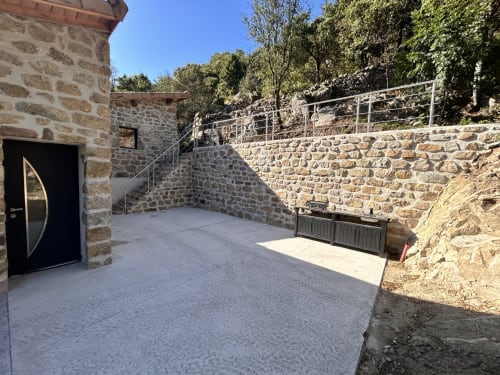 Stone courtyard with modern amenities at Gîte Les Oliviers d'Ardèche in Chalencon, featuring mountain views and rustic